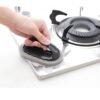 Brosse éponge abrasive avec poignée utilisée sur une surface de cuisine