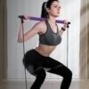9 1024x1024 2x d49376f3 f465 4a5f 960f 3e97599749c6.jpg Exercice avec une barre de Pilates violette, élastiques et sangles pour les pieds