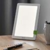 Lampe Beurer TL 30 blanche avec support vert sur une table